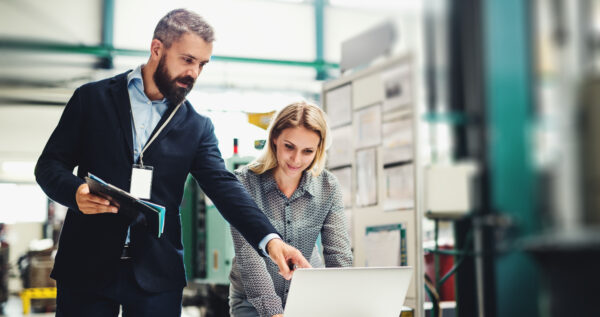 A Portrait Of An Industrial Man And Woman Engineer With Laptop In A Factory, Working.